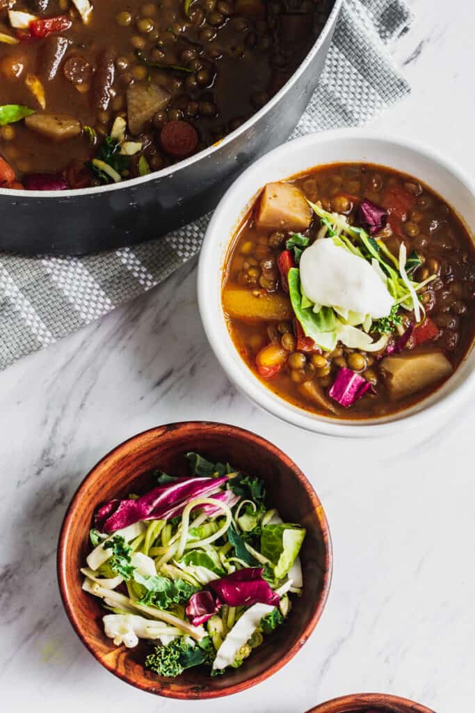 vegan lentil soup with veggies, potatoes, and greens in bowls with coconut yogurt