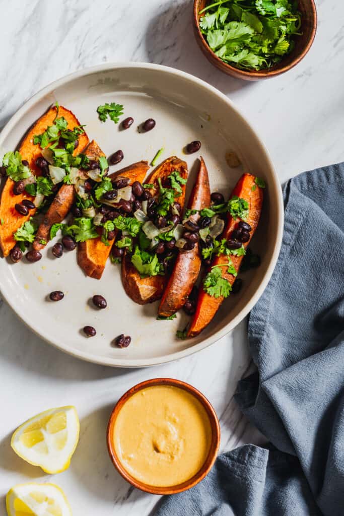 baked sweet potato wedges with black beans and cilantro and siete cashew cheese