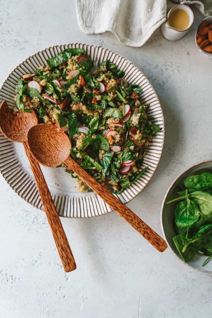 quinoa salad recipe, turmeric tea, spinach radishes, almonds on decorative plate with wooden spoons