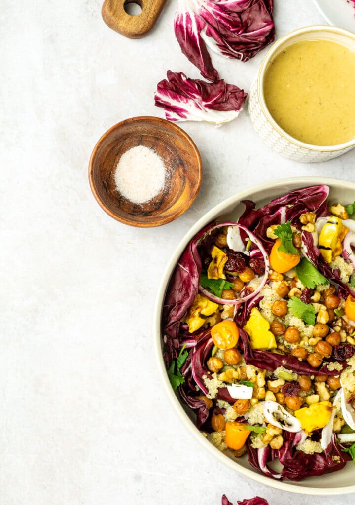 winter salad recipe with radicchio, chickpeas, squash, tomatoes, quinoa, citrus vinaigrette, in tan bowl
