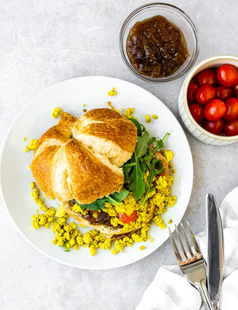 tofu scramble recipe with tomatoes, fig preserve, spinach, and vegan croissant
