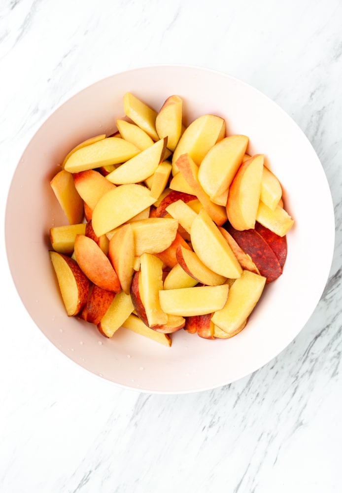 sliced peaches in a pink bowl
